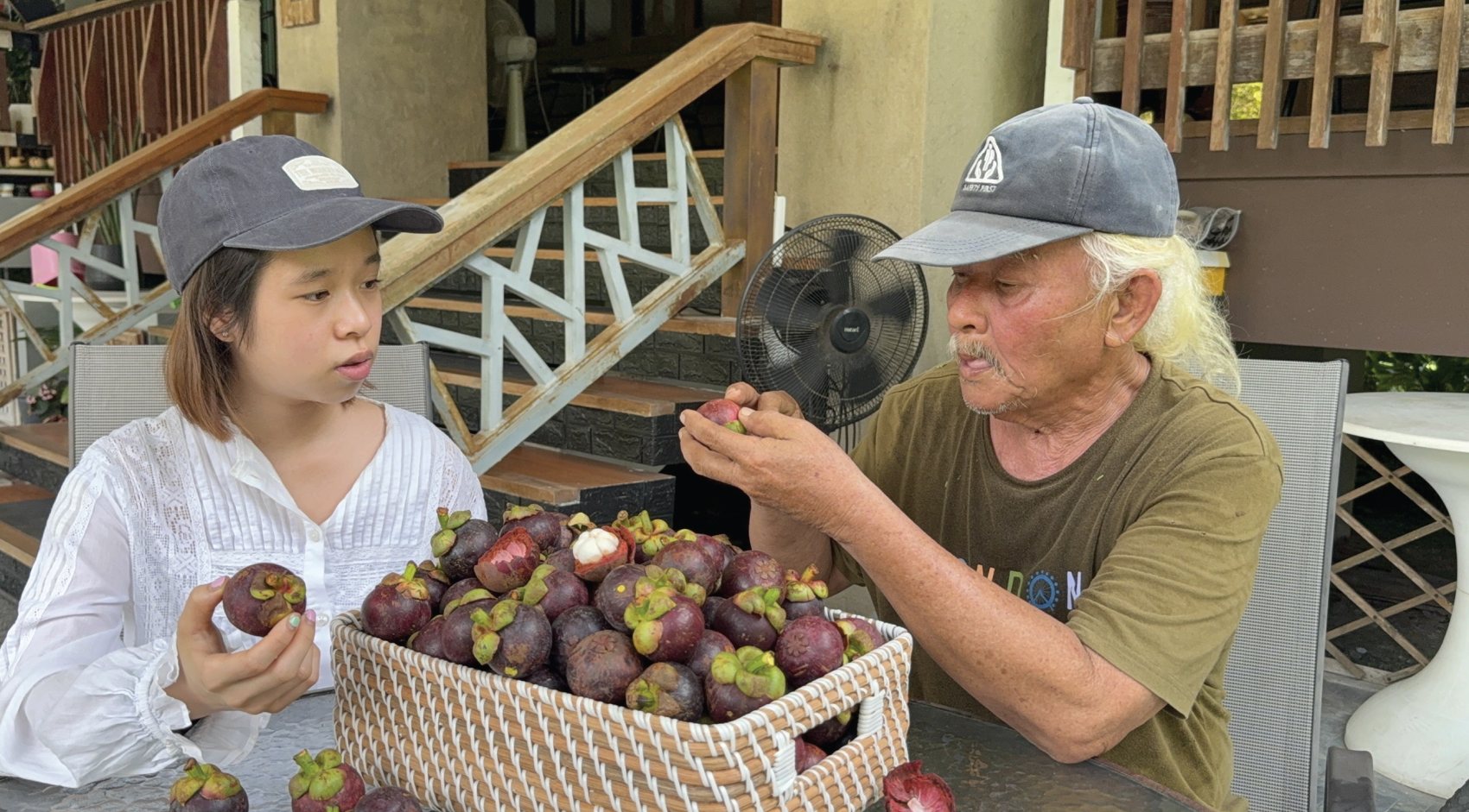 Annie and the farmer sorting fresh mangosteens at a table