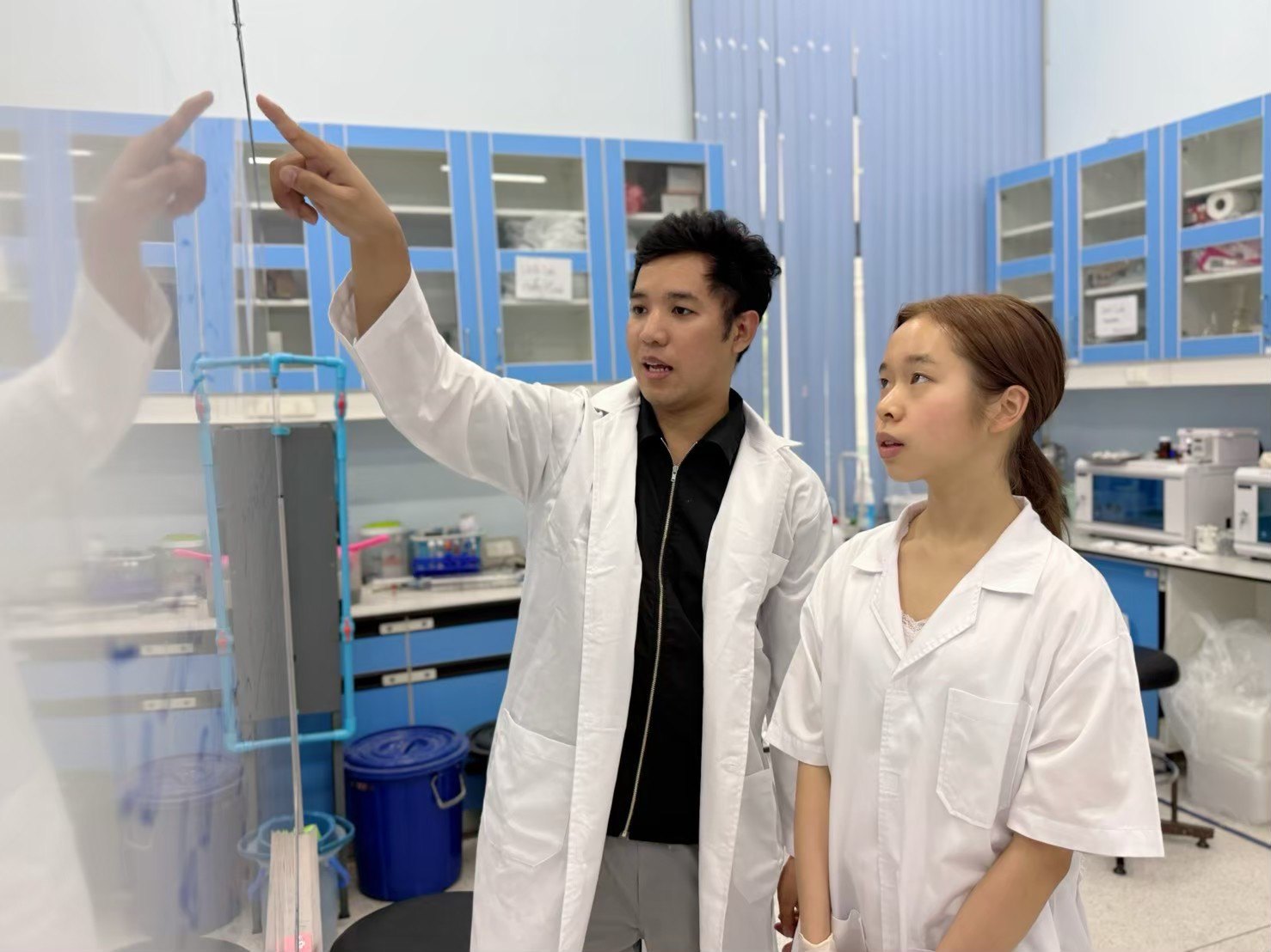 A professor explaining an experiment to Annie in the environmental engineering laboratory