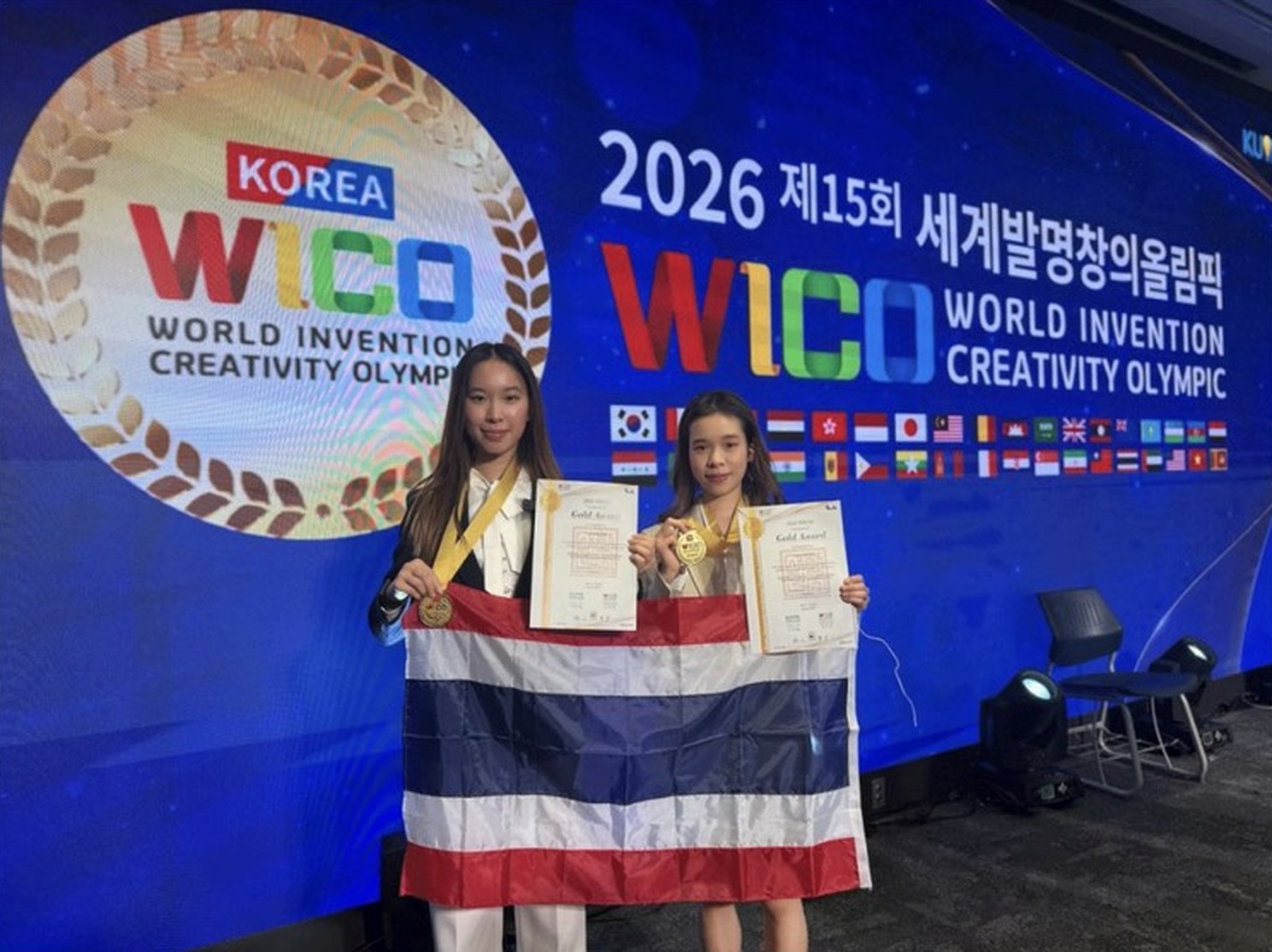 Annie and Winnie holding the Thai flag with their WICO 2026 gold medals and certificates
