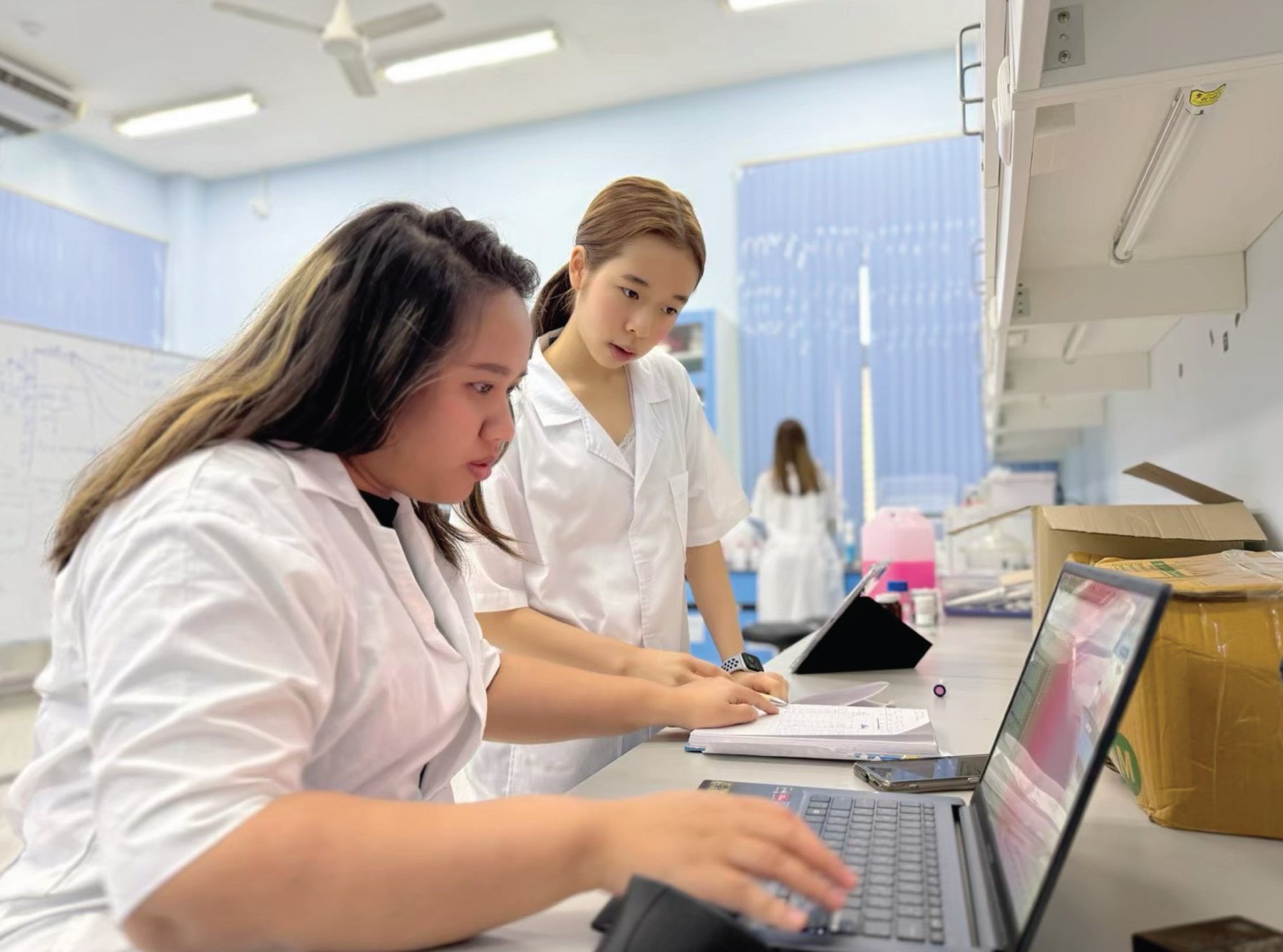 Annie and a research teammate recording results on a laptop