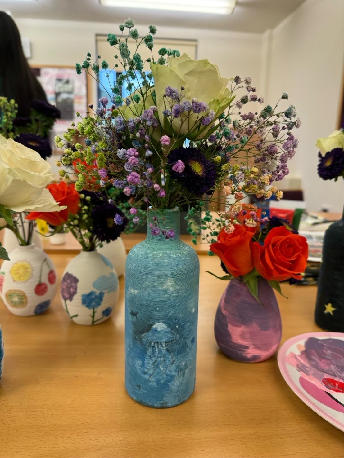 Flower arrangements in hand-painted vases made at a Wellbeing Wonders Club session
